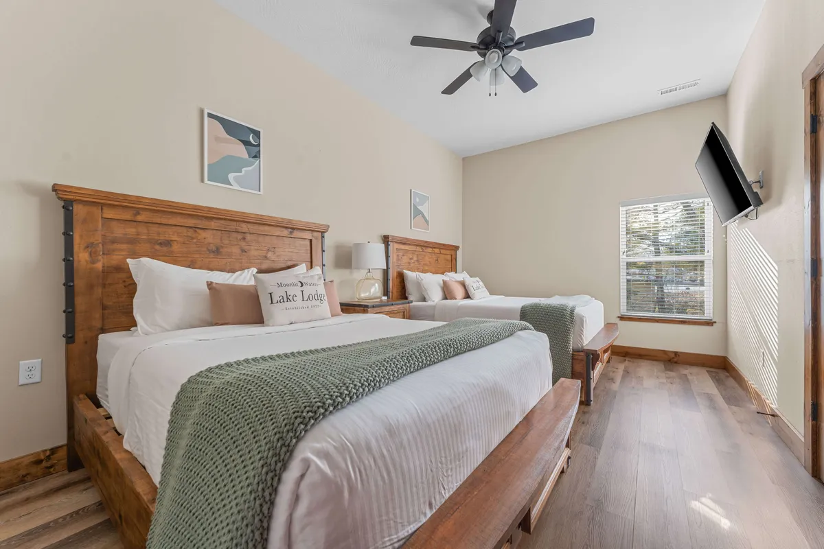 A warmly decorated bedroom featuring wooden beds, decorative pillows, artwork on the walls, and sunlight streaming in from a window. This layout feels spacious and inviting, capturing a sense of tranquility and togetherness.