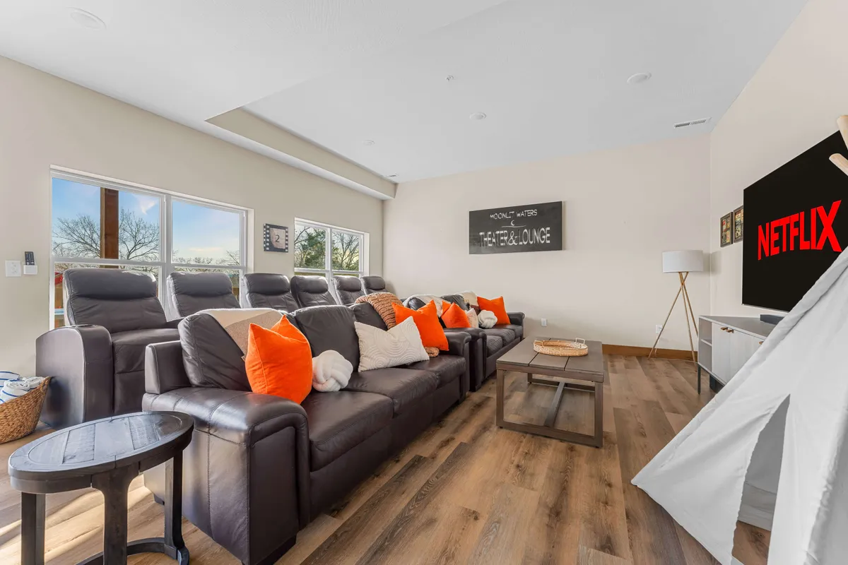 A stylish lounge space designed for entertainment, with a large screen displaying the Netflix logo as the focal point. Comfortable seating with decorative pillows surrounds a wooden coffee table, while playful touches like a children's play tent add a family-friendly vibe.